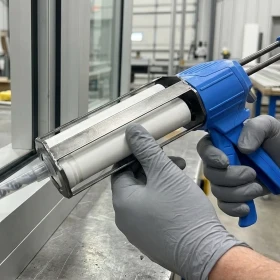 worker using dual cartridge dispensing gun for two component adhesive