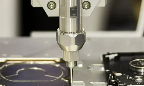 Close-up of an automated pick-and-place machine performing precision electronics assembly, placing a surface-mount component onto a PCB