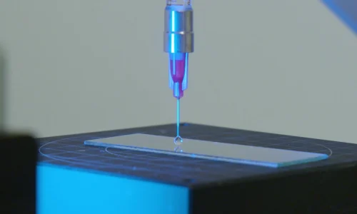 Close-up of automated dispensing system delivering a perfect micro-dot of adhesive
