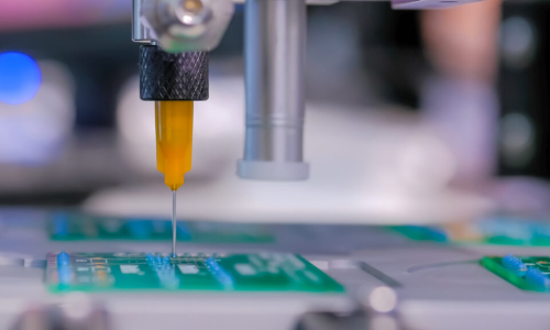 Robotic dispensing nozzle precisely applying adhesive or potting compound onto populated electronic circuit board