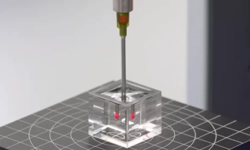 Long flexible dispensing tip accurately placing tiny red micro-dots inside a transparent fixture