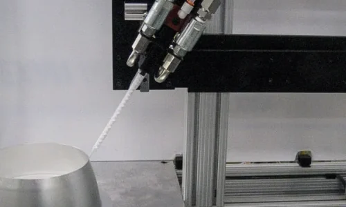 Close-up of an automated dispensing nozzle extruding white material onto a metallic electronic component during precision manufacturing process